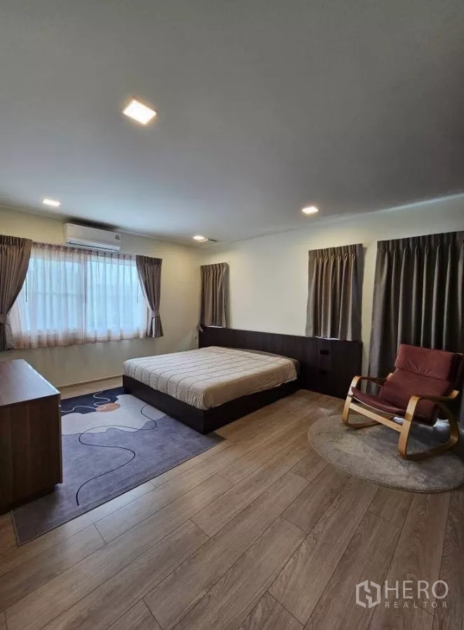 Detached House for rent in Bang Phli, Samut Prakan - Spacious master bedroom with double bed, curtains and a reading chair.