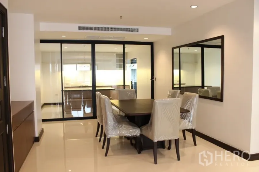 คอนโด ให้เช่าในWatthana, Bangkok - ห้องทานอาหารพร้อมโต๊ะเก้าอี้ กระจกเงาบนผนัง และทางเข้าสู่ครัวด้วยประตูกระจกเลื่อน