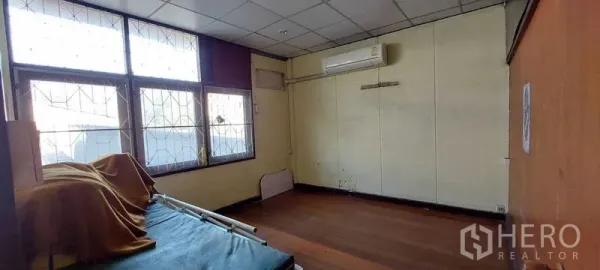 Townhouse for sale - Spacious bedroom with large gridded windows, wall air-conditioner, and wood flooring.