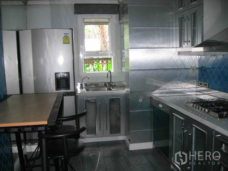 Detached House for rent in Watthana, Bangkok - Fitted kitchen with stainless-steel cabinets, gas cooktop, breakfast counter and refrigerator.
