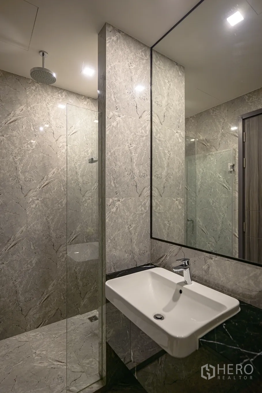 Condominium for rent in Watthana, Bangkok - Modern bathroom with large mirror, vanity and glass-enclosed shower.
