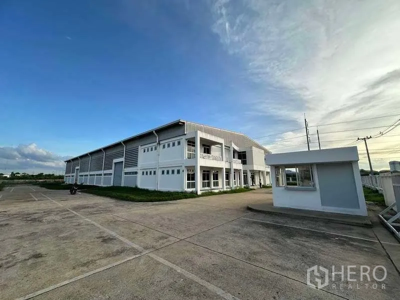 Factory for rent in Khlong Luang, Pathum Thani - Side view of factory with guardhouse, metal-clad walls and broad driveway for trucks.