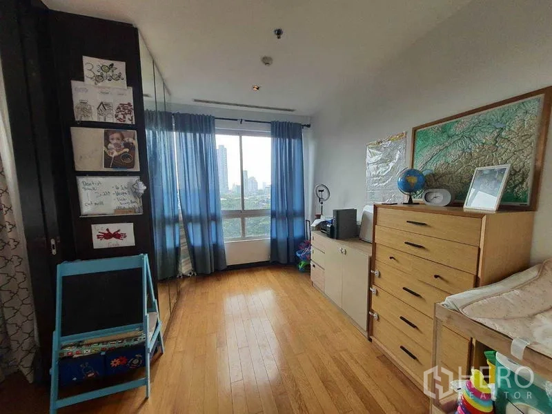 公寓 出租在Yan Nawa, Bangkok - 采光充足的卧室/书房，蓝色窗帘、斗柜与城市景观窗。
