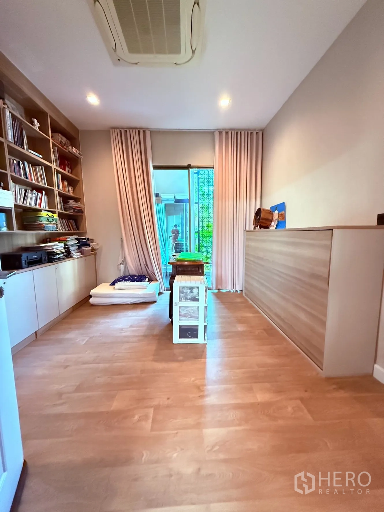 Detached House for rent or sale in Prawet, Bangkok - Multipurpose room with built-in bookshelves, wood flooring, and sliding door to a small patio.