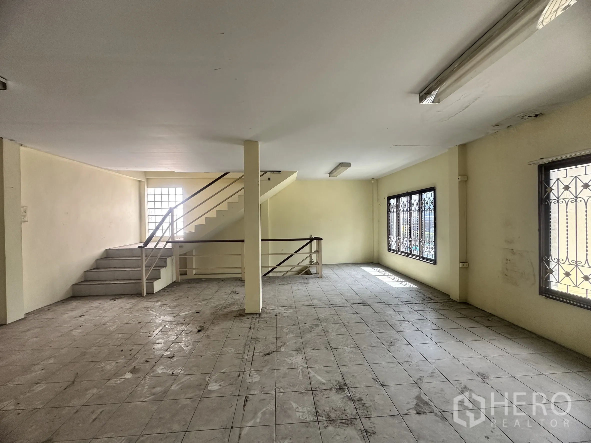 Factory for sale in Bang Bua Thong, Nonthaburi - Open-plan office level with staircase, window grilles, and natural light.