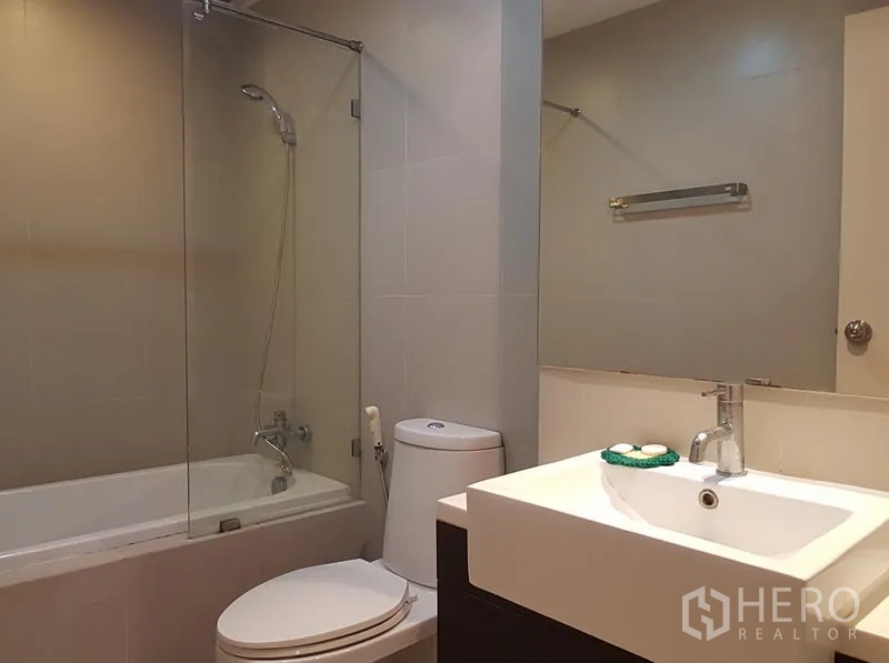 Condominium for rent in Khlong Toei, Bangkok - Modern bathroom with bathtub and glass shower screen, vanity and toilet.