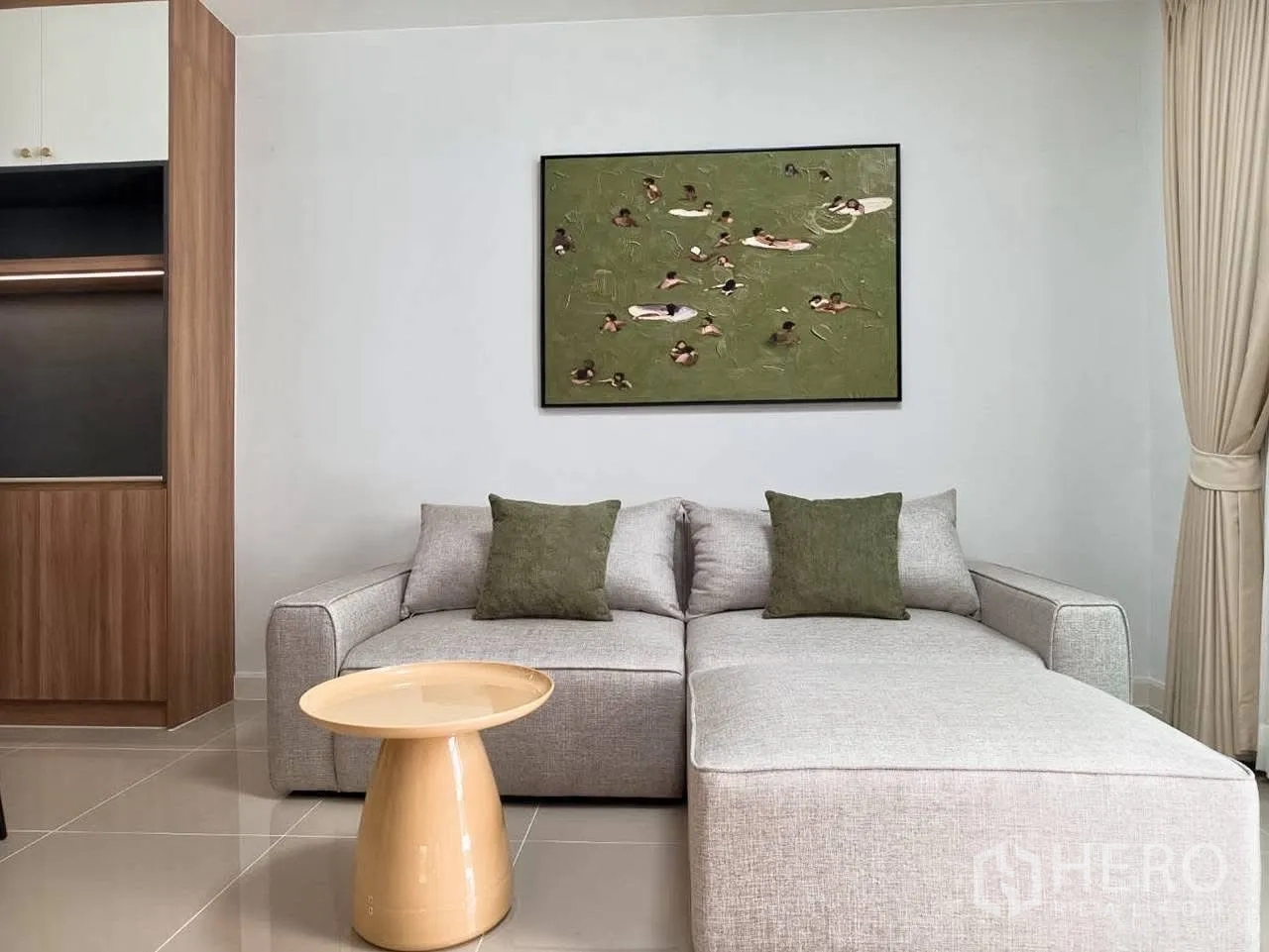 ทาวน์เฮาส์ for rent in Bang Phli, Samut Prakan - โซฟาผ้าแอลเชฟสีเทาพร้อมหมอนสีเขียวและภาพแขวนผนังข้างผ้าม่านสีเบจ