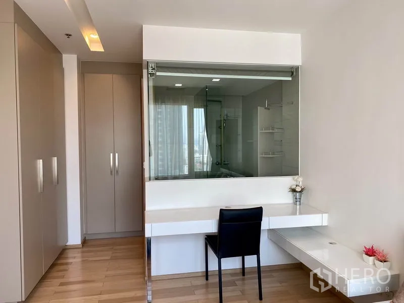 Condominium for rent in Khlong Toei, Bangkok - Bedroom with built-in wardrobes, dressing desk and a glass window to the bathroom.