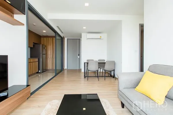 公寓 出租在Watthana, Bangkok - 从客厅望向餐区与玻璃推拉门后的独立厨房，木质橱柜与电器齐全。