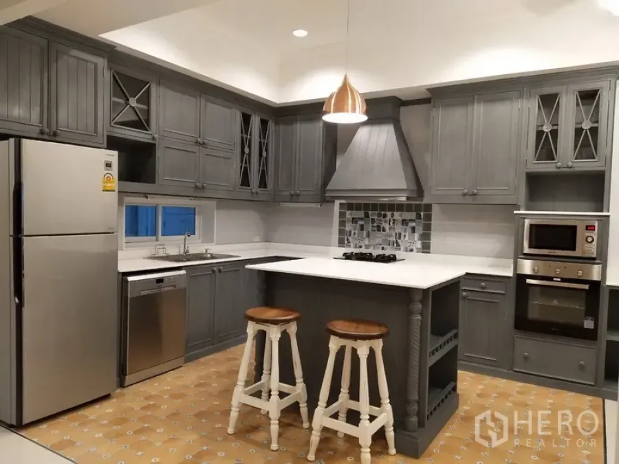 Townhouse for rent in Mueang Samut Prakan, Samut Prakan - Modern grey kitchen with island, gas cooktop, pendant light, and stainless appliances.