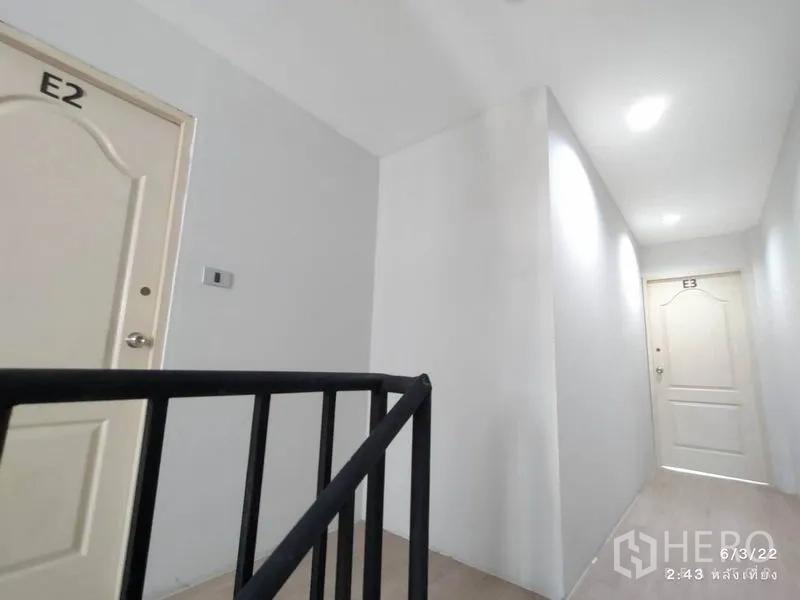 零售空间 出租在Phaya Thai, Bangkok - 干净走廊，白色E2与E3房门，旁有黑色金属楼梯扶手。