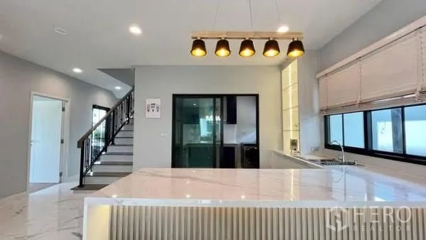 独栋房屋 for rent or sale in Bang Phli, Samut Prakan - 厨房中岛下吊灯，旁有楼梯与移门