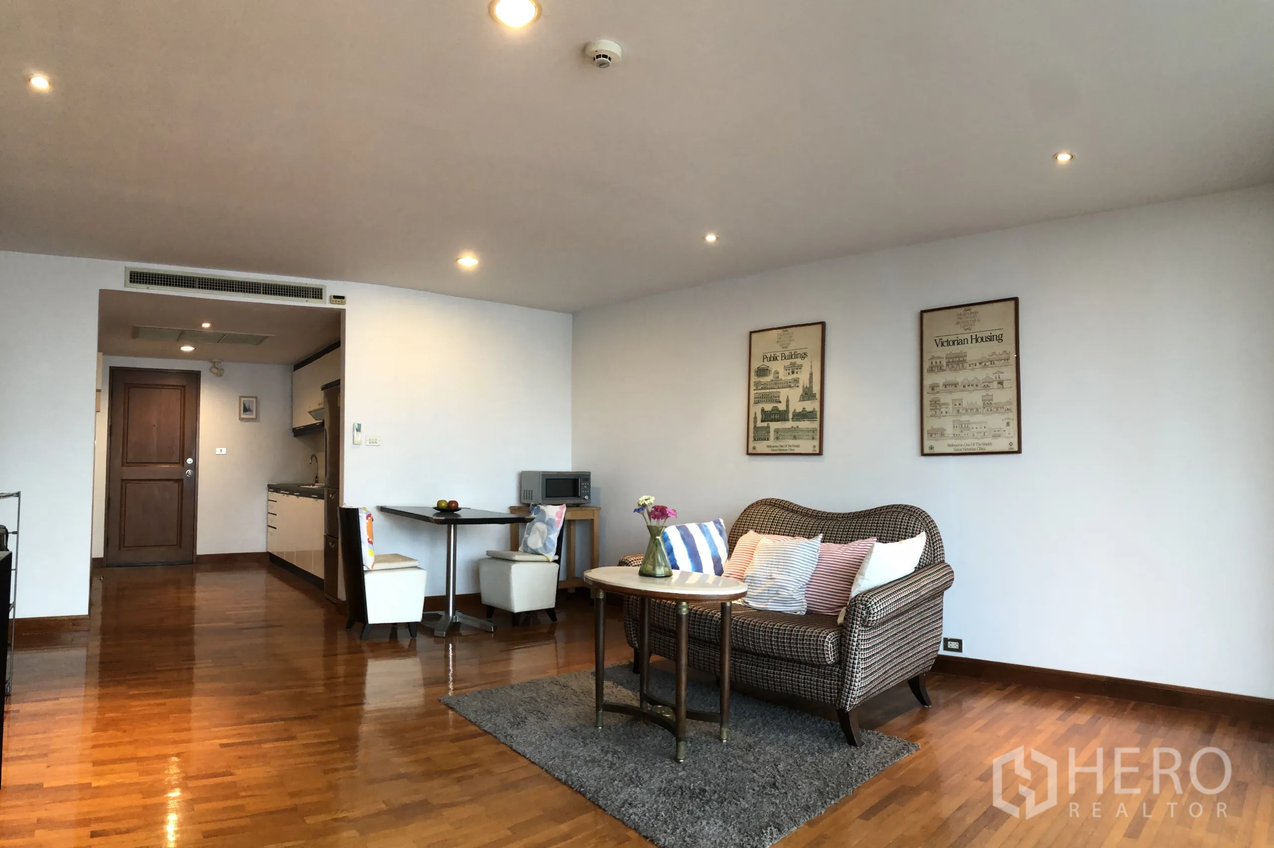 Condominium for rent in Khlong Toei, Bangkok - Open-plan living and dining area with compact kitchenette, small dining set and recessed lighting.