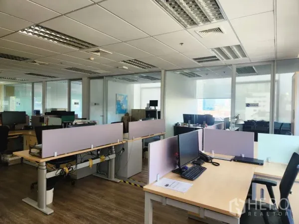 办公空间 出租 - 开放工区配书桌与显示器，旁有玻璃隔断会议室和吊顶照明。