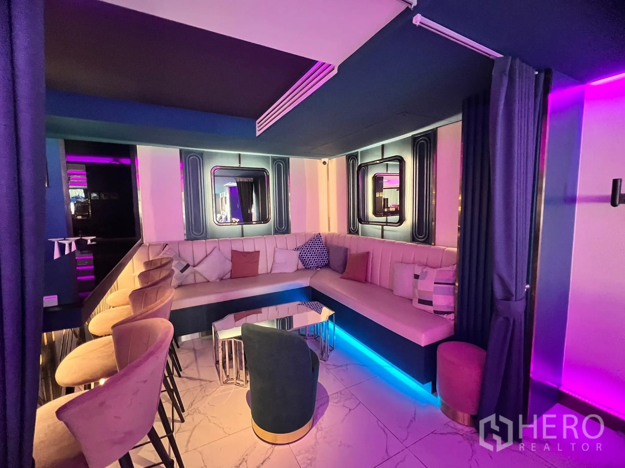 Retail Space for rent - Semi-private booth with curved sofa, bar stools, accent mirrors and blue under-seat lighting.