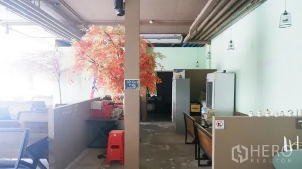 Retail Space for rent in Watthana, Bangkok - Open-plan retail interior with booth seating, pendant lights, exposed ceiling pipes, and decorative trees.