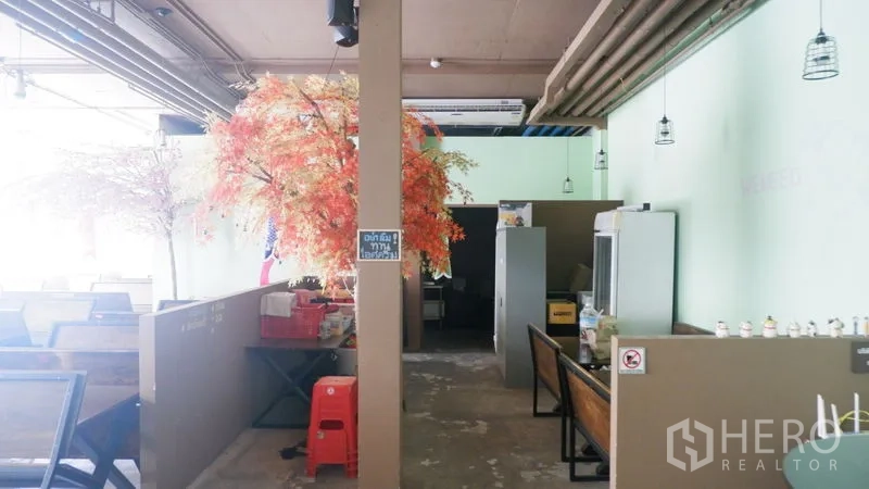 Retail Space for rent in Watthana, Bangkok - Open-plan retail interior with booth seating, pendant lights, exposed ceiling pipes, and decorative trees.