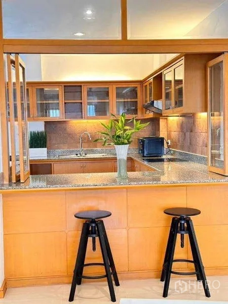 Apartment for rent - Breakfast bar facing a wood-cabinet kitchen with two black stools.