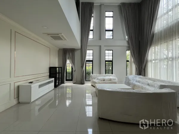 Detached House for rent or sale in Prawet, Bangkok - Bright lounge with floor-to-ceiling windows and glossy tile floors in the living area.
