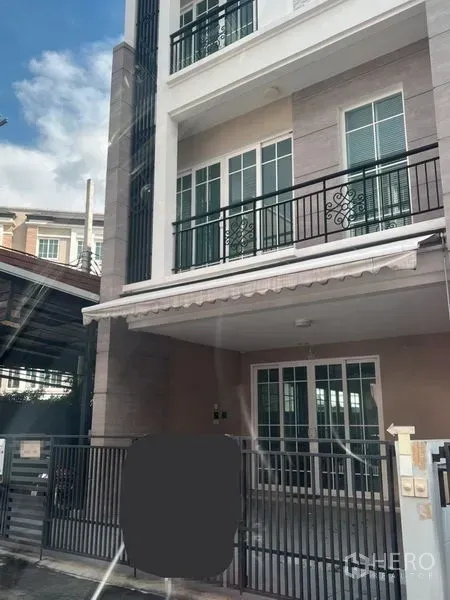 Home Office for rent or sale - Three-storey home office exterior with balconies, sliding glass doors, and a gated carport in Bang Na, Bangkok.