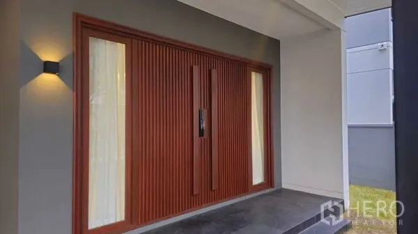 Detached House for sale in Sai Mai, Bangkok - Wood-slat front door with sidelights and porch lighting at the Bangkok detached house.
