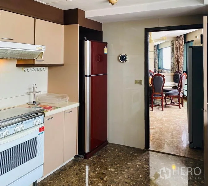 Condominium for rent in Khlong Toei, Bangkok - Enclosed kitchen with beige cabinets, range hood and two-door refrigerator.
