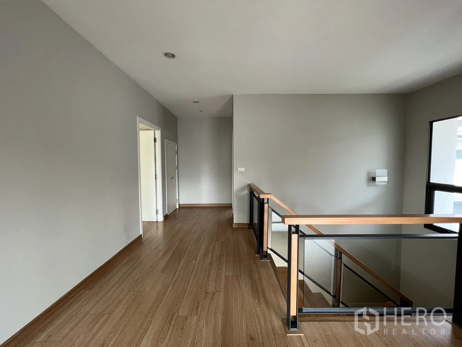 Detached House for sale in Suan Luang, Bangkok - Upper hallway with glass balustrade and wood flooring.