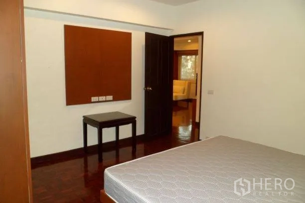 公寓 出租在Pathum Wan, Bangkok - 次卧配床垫与边几，深色木门通向客厅