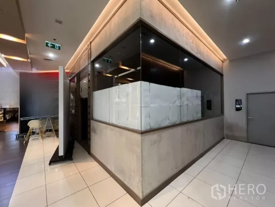 零售空间 出租 - 商场内玻璃转角店面，走廊为瓷砖地，顶灯暖色。