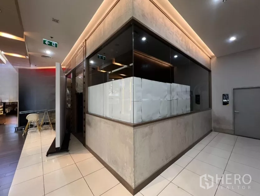 零售空间 出租 - 商场内玻璃转角店面，走廊为瓷砖地，顶灯暖色。