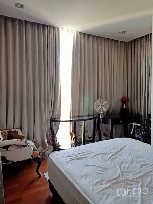 Condominium for rent in Khlong Toei, Bangkok - Bedroom featuring tall curtains, white mattress, writing desk and hardwood floors.