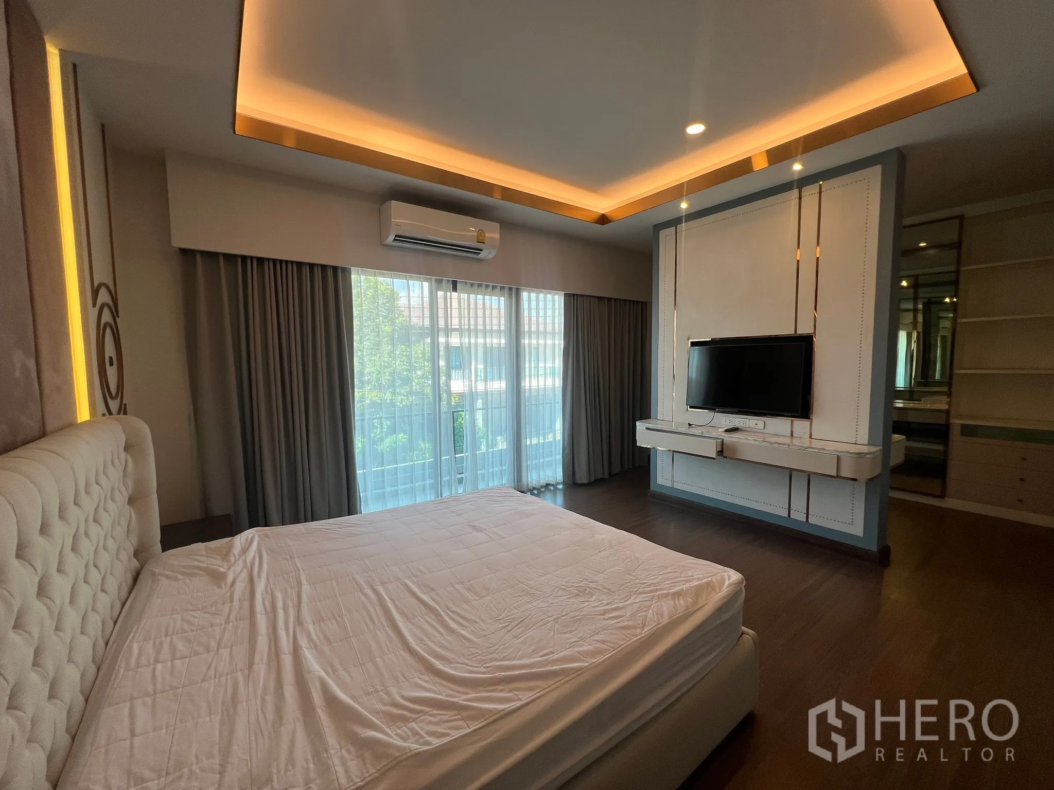 Detached House for rent or sale in Prawet, Bangkok - Bedroom with sliding glass doors to balcony and wall-mounted TV.