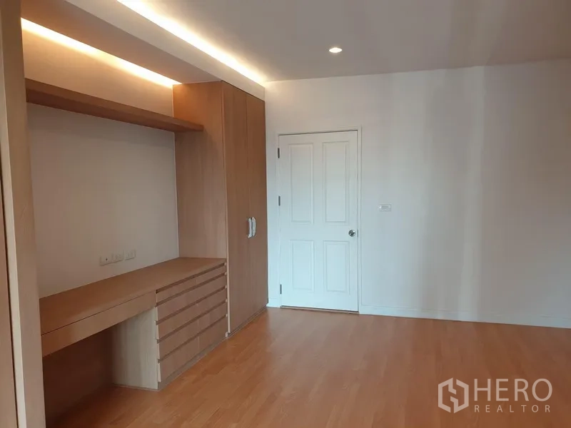 Condominium for rent in Watthana, Bangkok - Bedroom with built-in desk, wardrobe, recessed lighting and wood flooring.