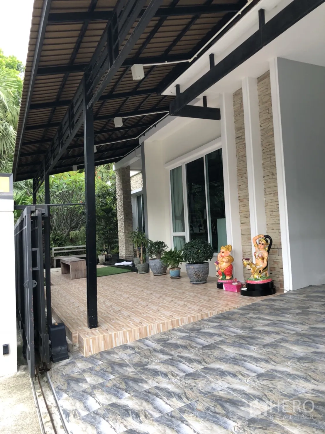 Detached House for rent or sale in Saphan Sung, Bangkok - Covered side terrace with tiled patio, potted plants and sliding doors