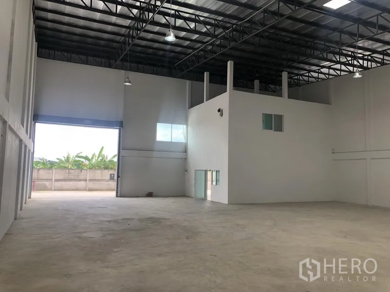 Factory for rent in Sai Noi, Nonthaburi - Another angle of the spacious warehouse showing mezzanine office and pendant lighting.