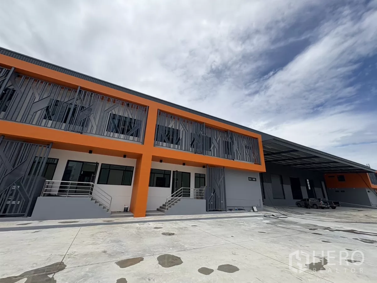 工厂 出租在Bang Pakong, Chachoengsao - 现代工厂广角外景，带有遮雨装卸区与宽阔混凝土车场。