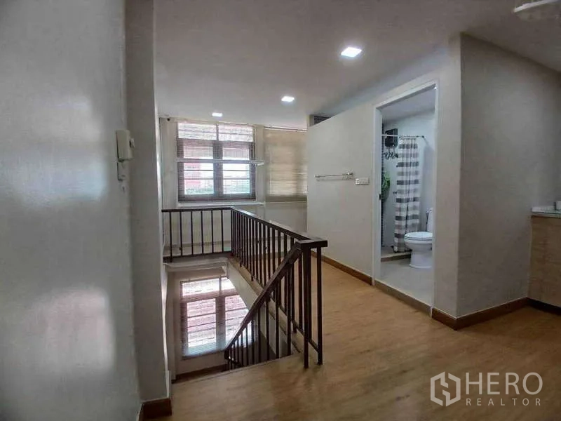 Shophouse for rent in Phra Khanong, Bangkok - Upper landing with wooden staircase, window light and a bathroom with shower and toilet.