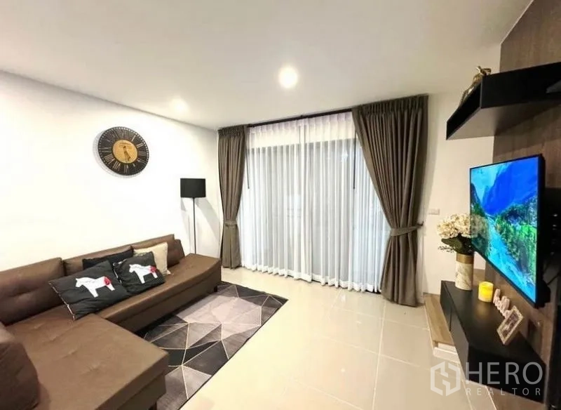Townhouse for rent - Living room with sliding glass doors, sheer curtains, and wall-mounted TV.
