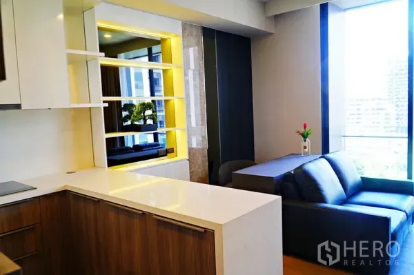 คอนโด ให้เช่าในWatthana, Bangkok - ครัวเปิดพร้อมเคาน์เตอร์หินควอตซ์ ชั้นโชว์ไฟซ่อน และโซฟาข้างหน้าต่างบานสูงวิวเมือง