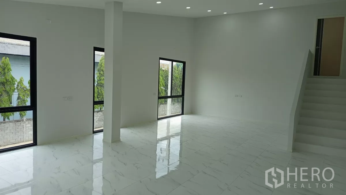Warehouse for rent or sale in Lam Luk Ka, Pathum Thani - Open-plan office area with tall windows and a staircase to the upper level.