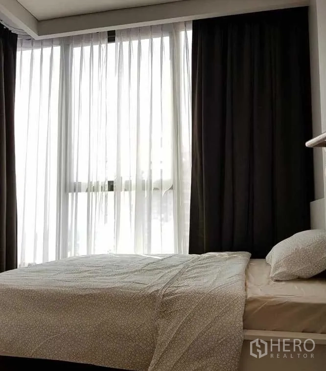 Condominium for rent in Khlong Toei, Bangkok - Bedroom corner with large windows, sheer and blackout curtains allowing natural light.