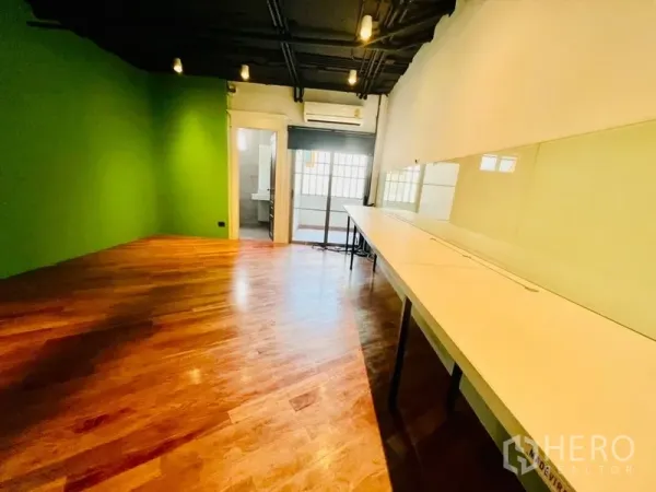 办公空间 出租在Khlong Toei, Bangkok - 带长条内置工位的工作间，绿色强调墙，旁通卫生间入口。