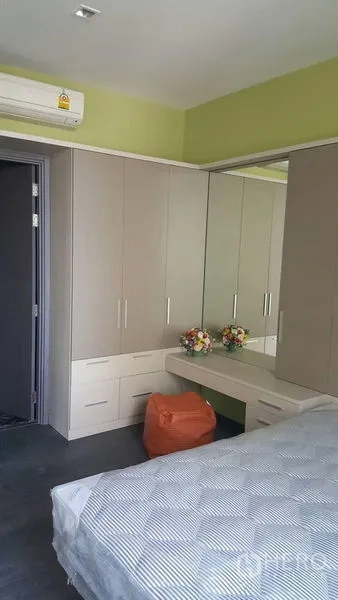 Condominium for rent in Watthana, Bangkok - Bedroom with built-in wardrobes, vanity with mirror, air conditioner and neatly made bed.