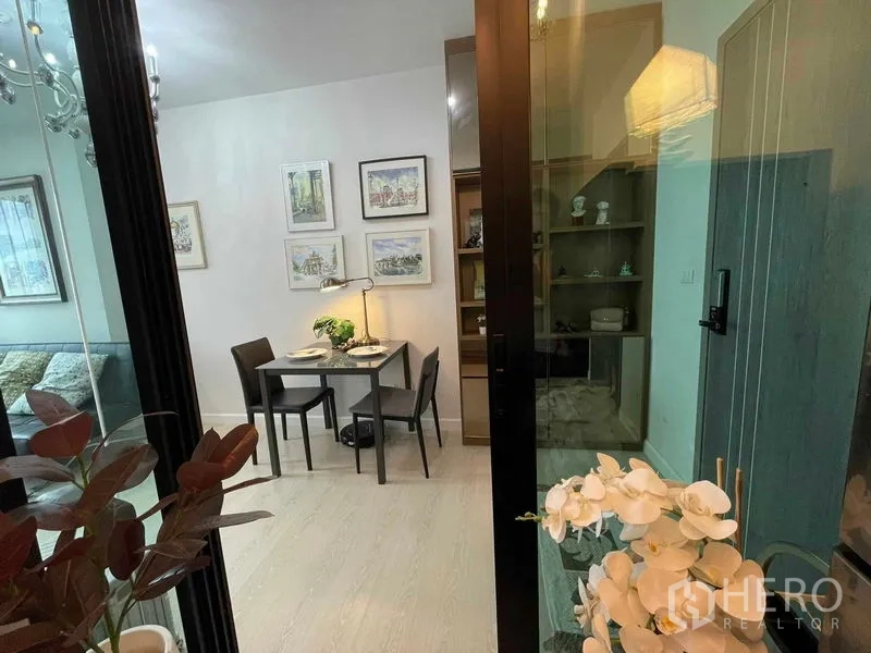 公寓 出售在Huai Khwang, Bangkok - 透过玻璃门看到用餐区，配展示柜与兰花装饰。