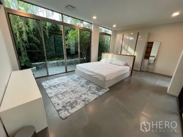 Detached House for rent - Master bedroom featuring full-height glass walls opening to a private garden terrace.