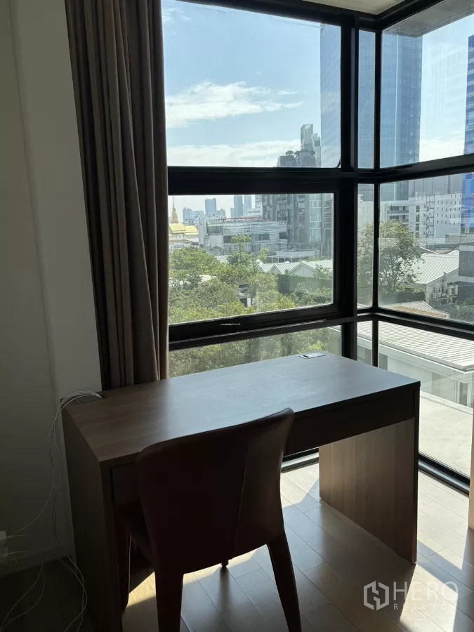 公寓 出售在Watthana, Bangkok - 转角全景窗旁的书桌，可俯瞰Ekkamai城市景色。