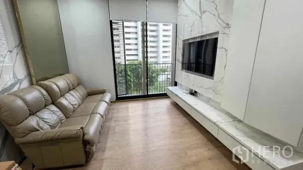 Condominium for rent in Watthana, Bangkok - Bright living room with marble TV wall, leather sofa and balcony view in a Watthana condo near BTS Asok.