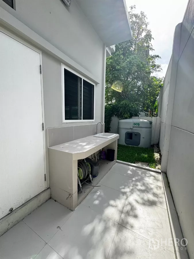 Detached House for rent in Prawet, Bangkok - Outdoor utility area with countertop sink, storage shelf and garden water tank.