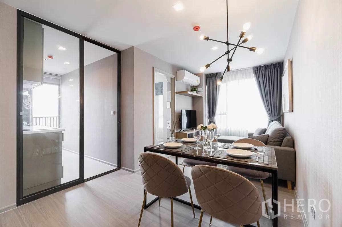 Condominium for rent in Chatuchak, Bangkok - Dining area set for four beside cozy living room and sliding glass to kitchen.