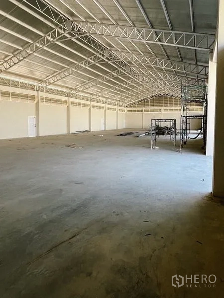 Warehouse for rent or sale - Spacious warehouse interior with steel truss roof and concrete floor.